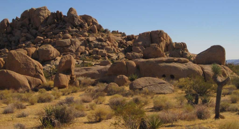 A large rock formation looms out of a desert landscape